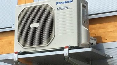 Eine Panasonic Klimaanlage mit Inverter-Technologie, montiert an einer Wand aus Holz und Metall.