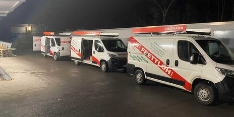 Drei Firmenfahrzeuge stehen in einer dunklen Umgebung, beleuchtet von Straßenlaternen, bereit für den Einsatz.